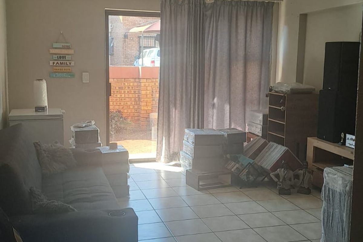 A living room featuring tiled flooring and a sliding glass door providing access to an outdoor area.
