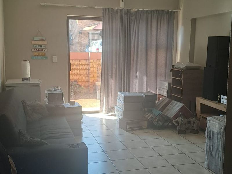 A living room featuring tiled flooring and a sliding glass door providing access to an outdoor area.