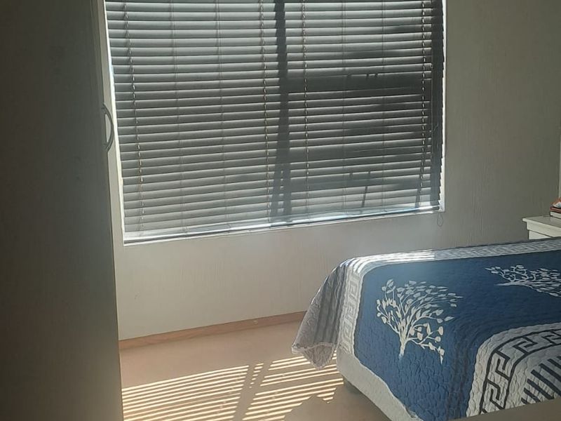 A bedroom featuring carpeted flooring and fitted venetian blinds, providing a functional space with natural light.