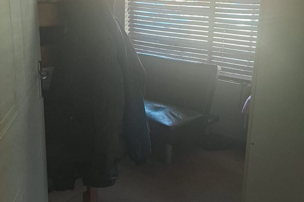 A bedroom featuring carpeted flooring and venetian blinds, currently obscured by strong backlight and low image quality.