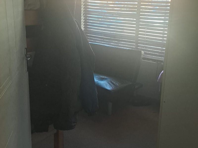 A bedroom featuring carpeted flooring and venetian blinds, currently obscured by strong backlight and low image quality.