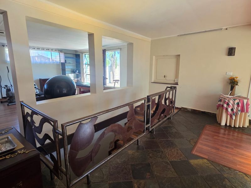 A spacious hallway featuring unique decorative metal balustrades, slate tile flooring, and a built-in wall niche, connecting to adjacent living areas.