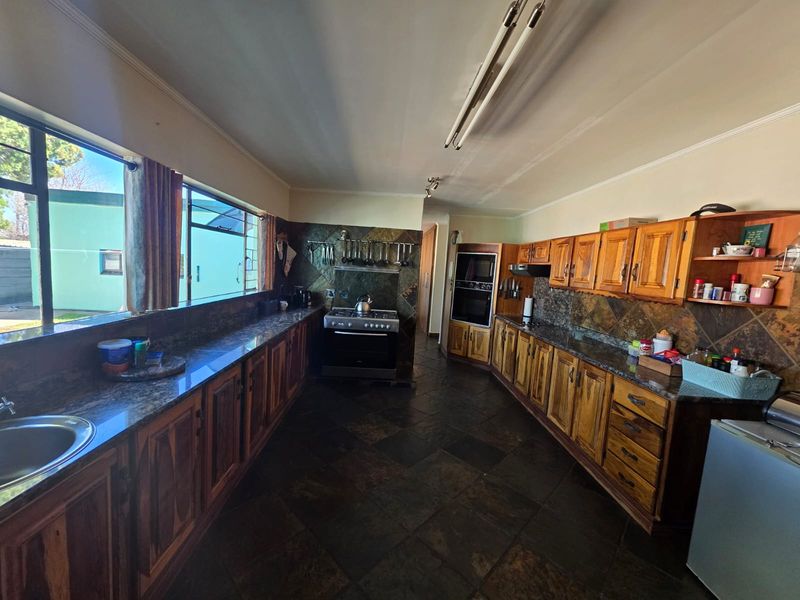 Spacious kitchen featuring extensive wooden cabinetry, granite countertops, slate tile flooring, and built-in oven, offering a functional layout with ample storage space.