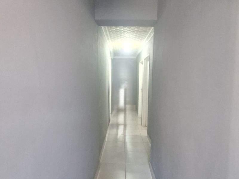 A clean, neutral-toned hallway featuring tiled flooring and simple ceiling finishes, providing a bright and functional transition space within the home.