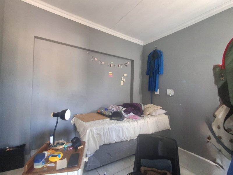 A bedroom featuring grey painted walls, coving, and tiled flooring, providing a functional space for rest.