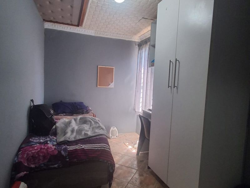 A compact bedroom featuring tiled flooring, a textured ceiling, and a built-in wardrobe.