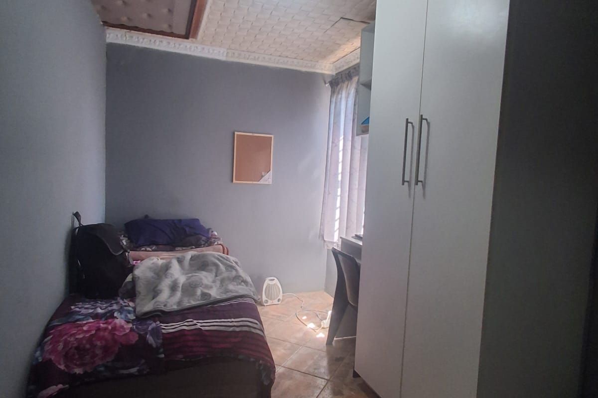A compact bedroom featuring tiled flooring, a textured ceiling, and a built-in wardrobe.