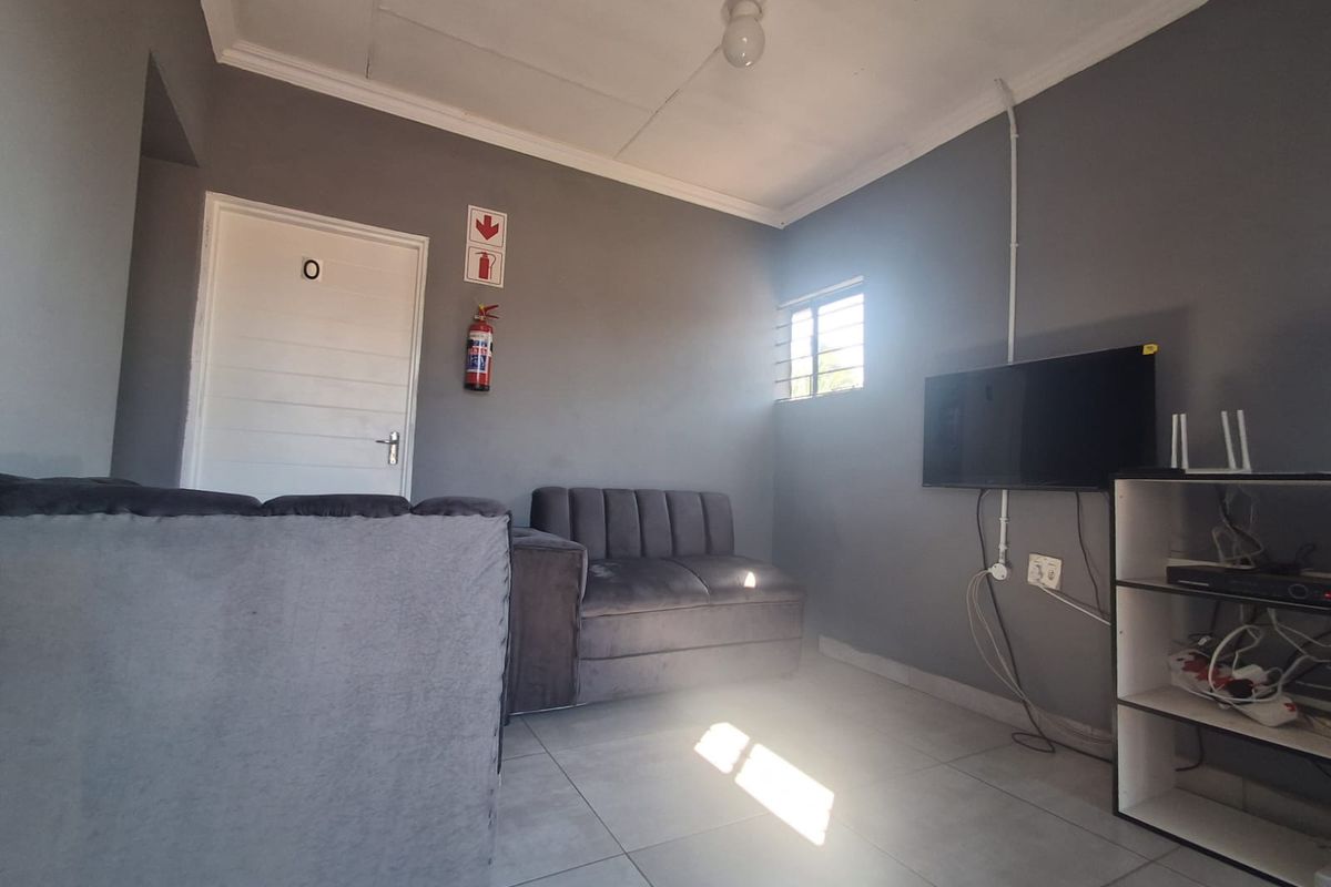 A compact living area featuring tiled flooring, grey walls, and a fire safety installation.