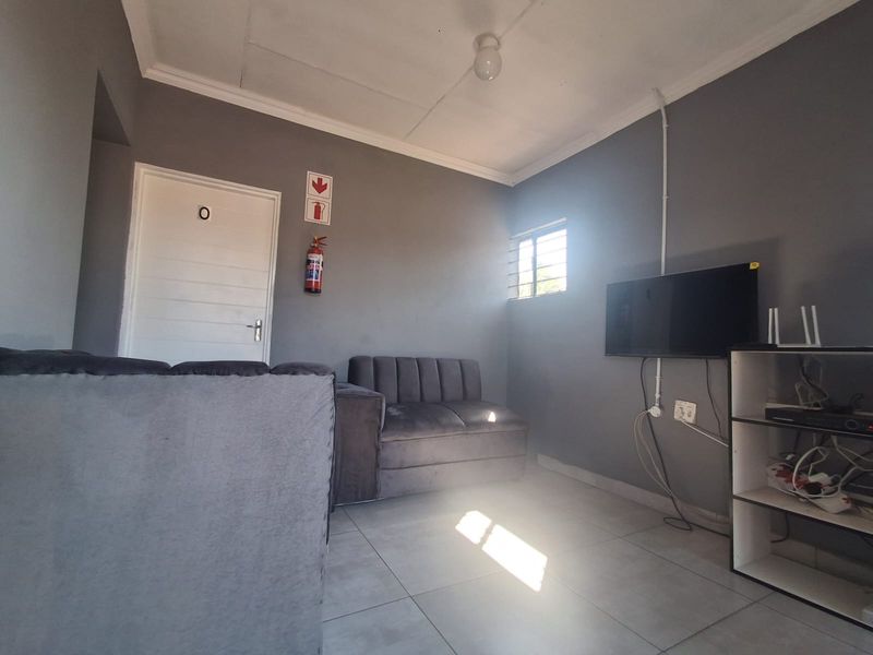 A compact living area featuring tiled flooring, grey walls, and a fire safety installation.