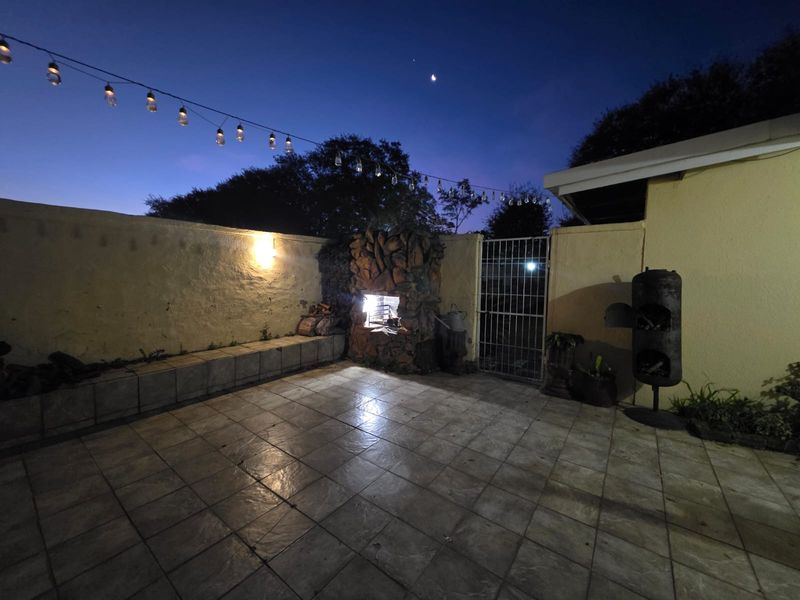 Outdoor patio area featuring tiled flooring, a built-in stone fireplace, and perimeter wall, perfect for evening entertaining.
