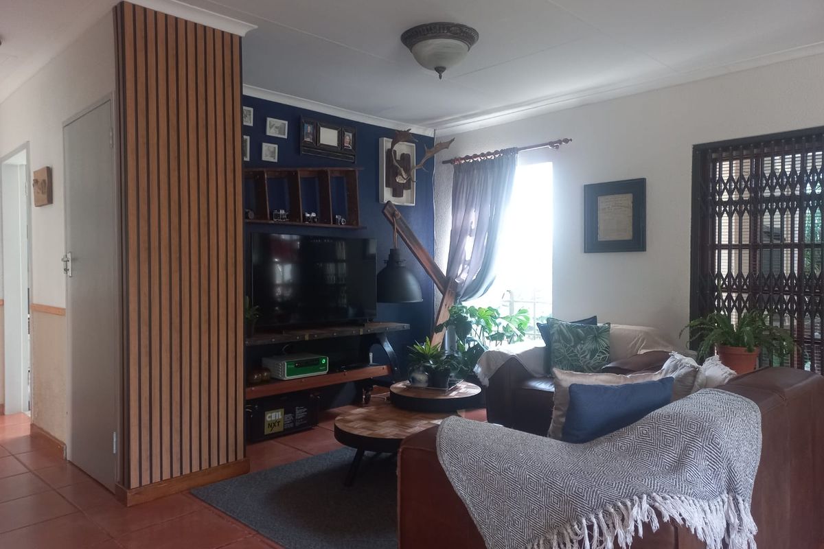 A cozy living room featuring decorative timber slat wall paneling, tiled flooring, and a secure entrance gate, creating a warm and inviting atmosphere.