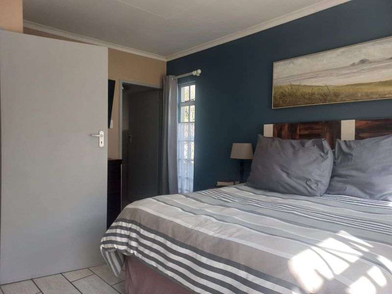 A bedroom featuring tiled flooring, a coved ceiling, and a casement window, with a dark blue accent wall.
