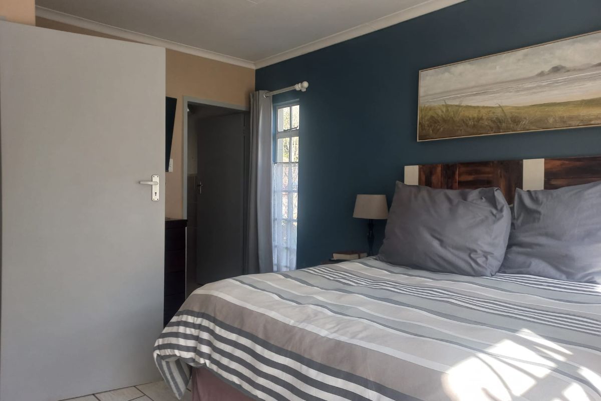 A bedroom featuring tiled flooring, a coved ceiling, and a casement window, with a dark blue accent wall.