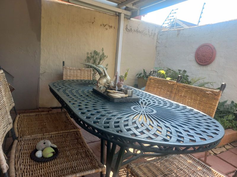 Covered outdoor patio area featuring paved flooring and perimeter walling with electric fencing, requiring maintenance to the wall finishes.