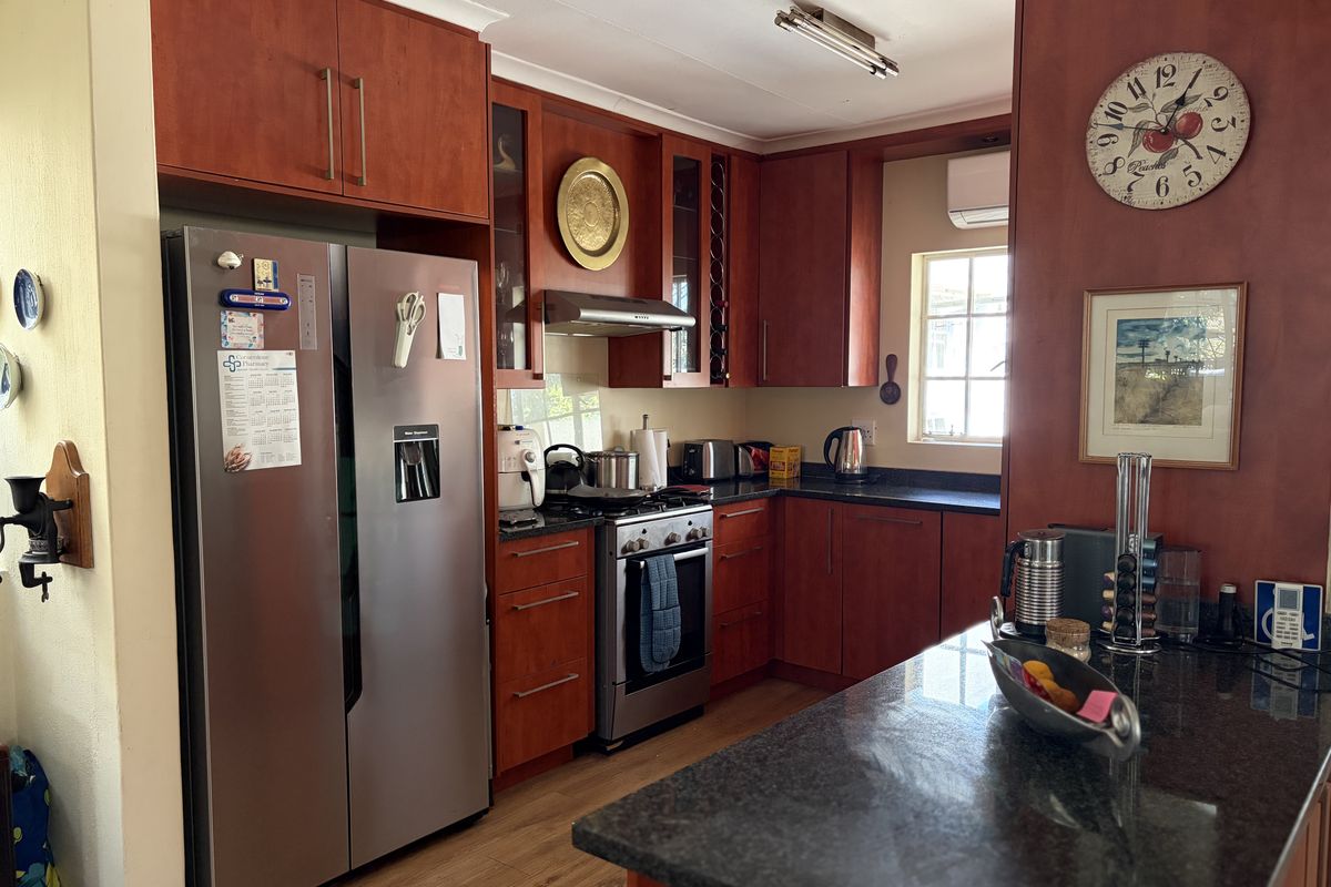 A functional kitchen featuring cherry wood cabinetry, granite countertops, and a stainless steel gas stove, offering a warm and practical cooking space.