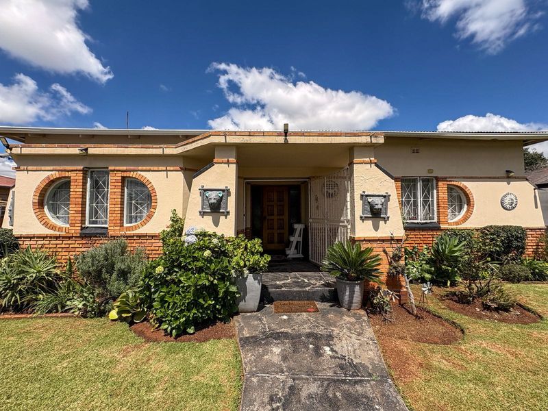 Front elevation of a house featuring distinctive circular windows, brick detailing, and a stone paved entrance path with established garden beds.