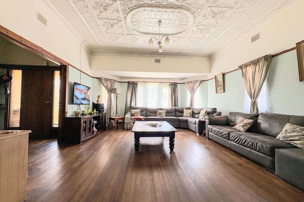 Spacious living room featuring original ornate pressed metal ceilings, polished timber flooring, and classic picture rails, offering a character-filled living space.