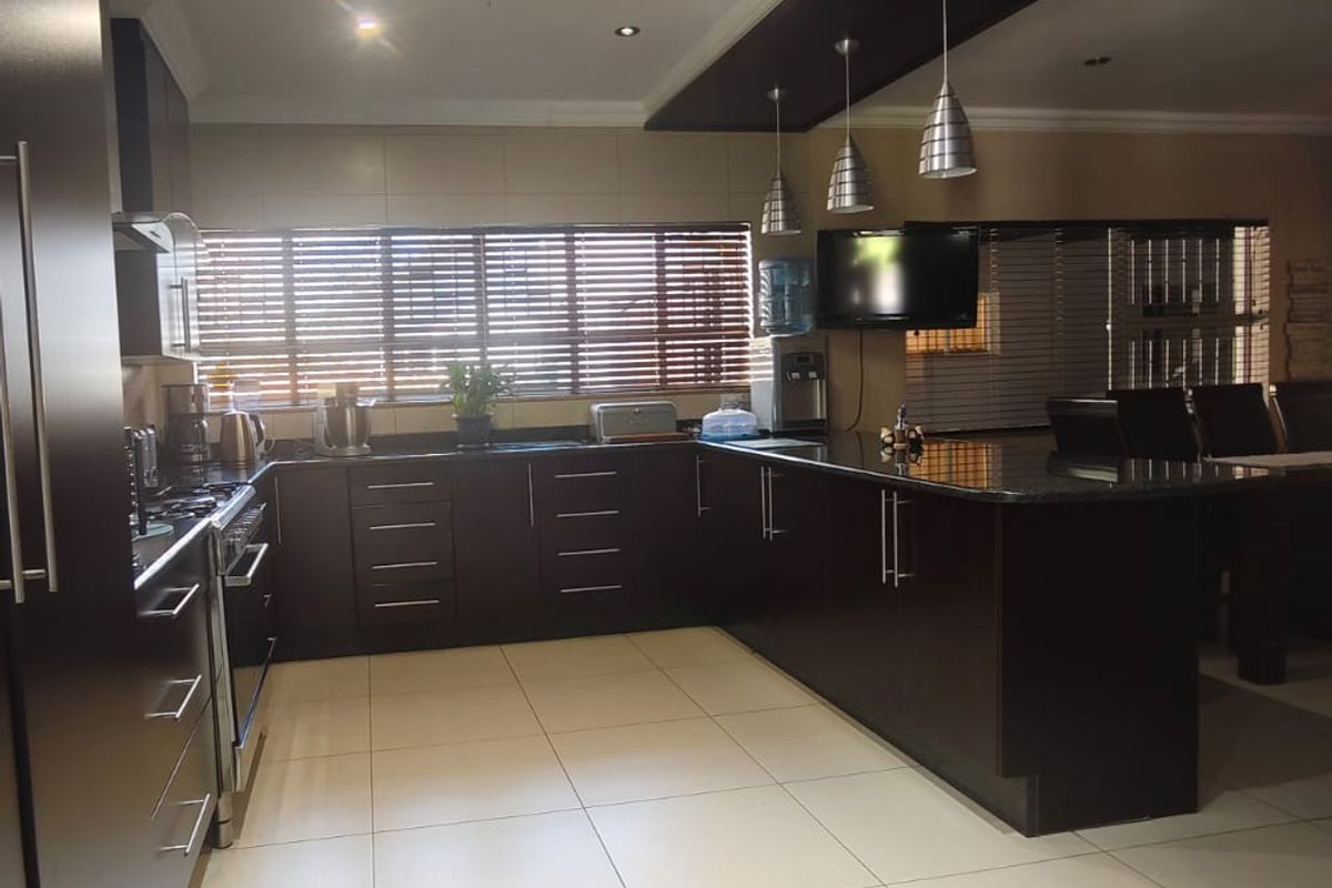 Modern kitchen featuring dark wood cabinetry, granite countertops, a gas stove, and a decorative bulkhead with integrated lighting.