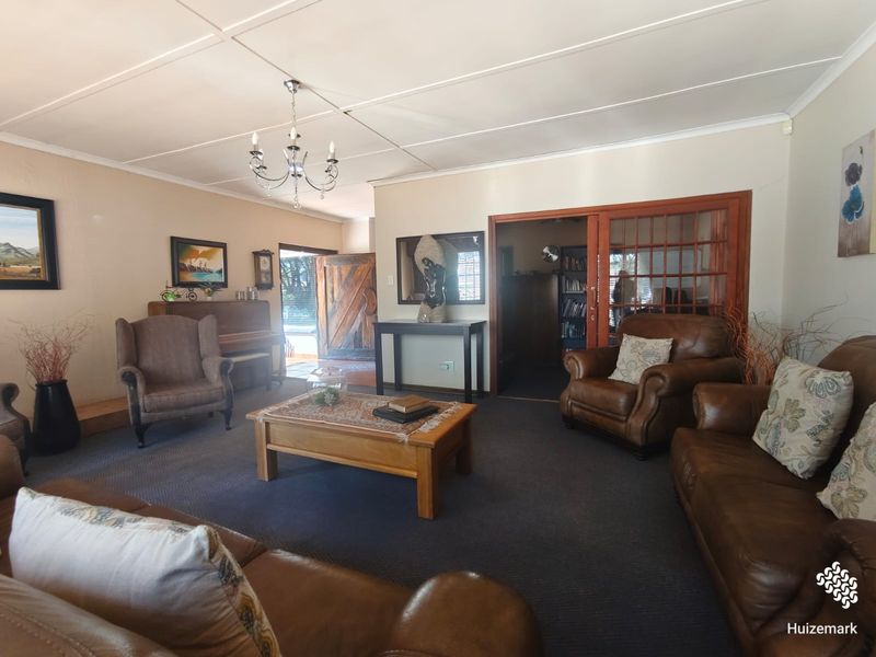 Spacious living room featuring a chandelier, carpeted flooring, and a sliding glass door leading to an adjacent room.