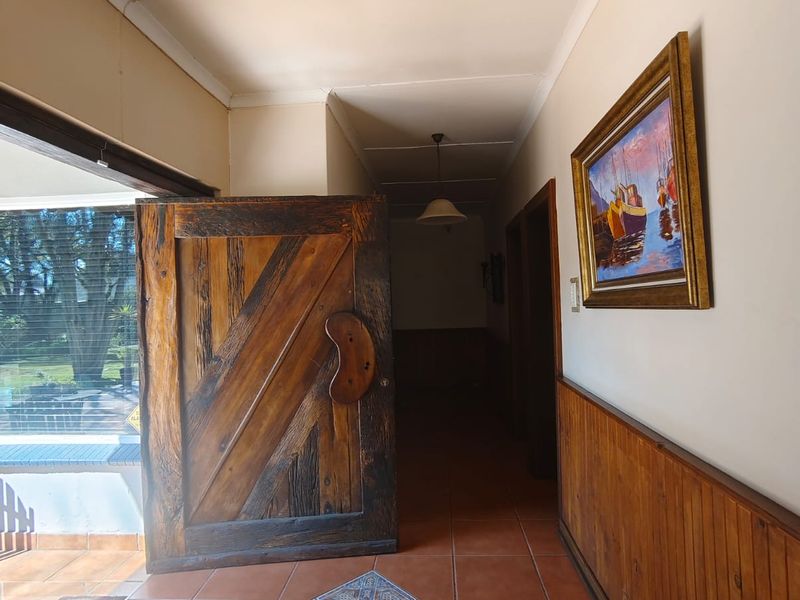 Entrance hall featuring terracotta floor tiles, timber wainscoting, and a solid timber front door leading into the home.