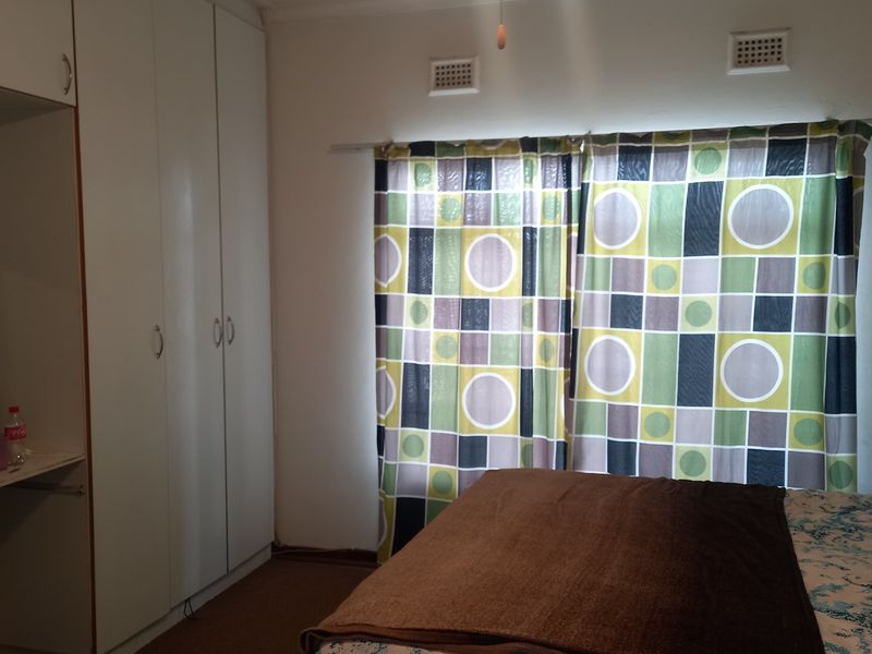 A bedroom featuring built-in cupboards, a ceiling fan, and wall-mounted air vents, providing functional storage and ventilation.