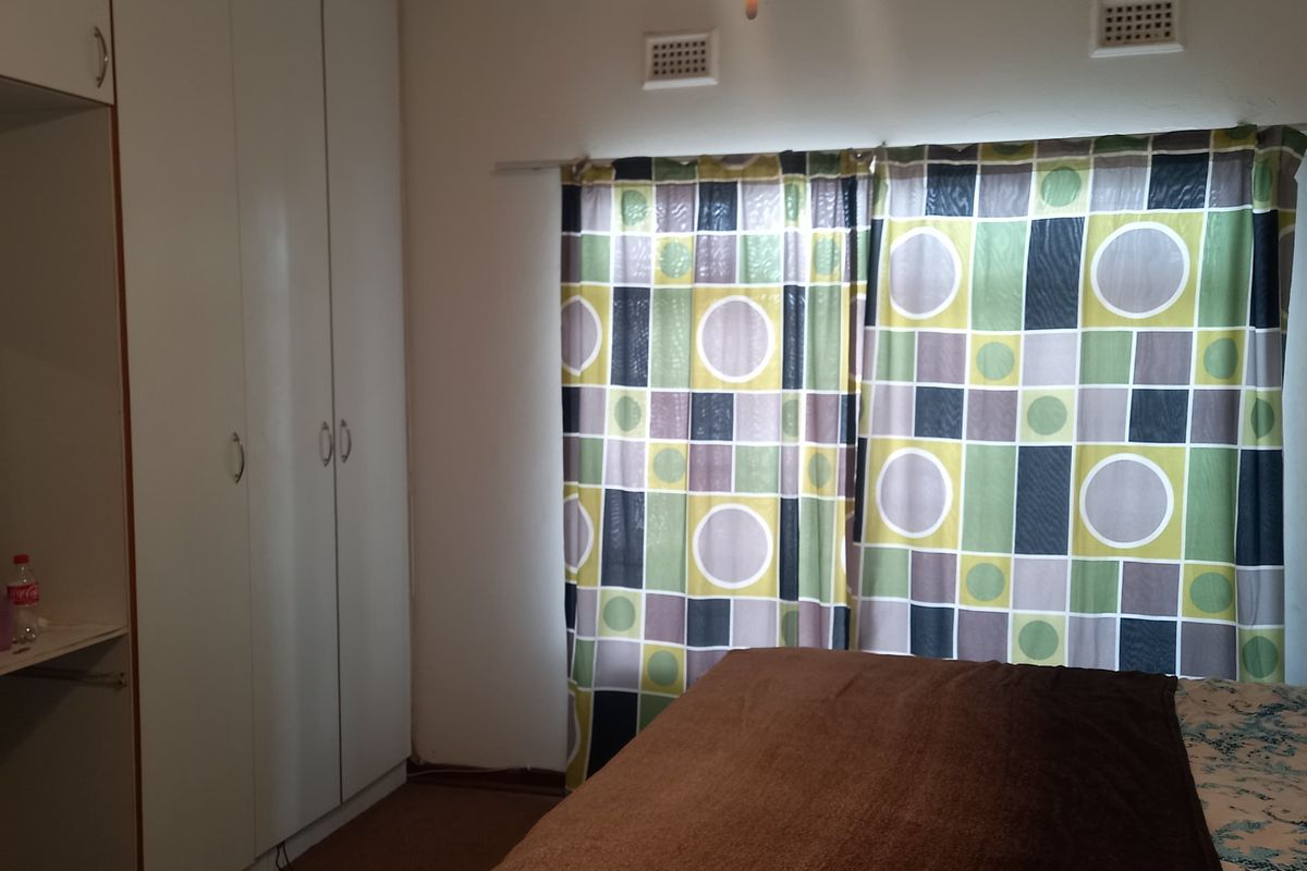 A bedroom featuring built-in cupboards, a ceiling fan, and wall-mounted air vents, providing functional storage and ventilation.