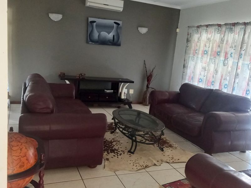 A living room featuring tiled flooring, a wall-mounted air conditioning unit, and ambient wall lighting.