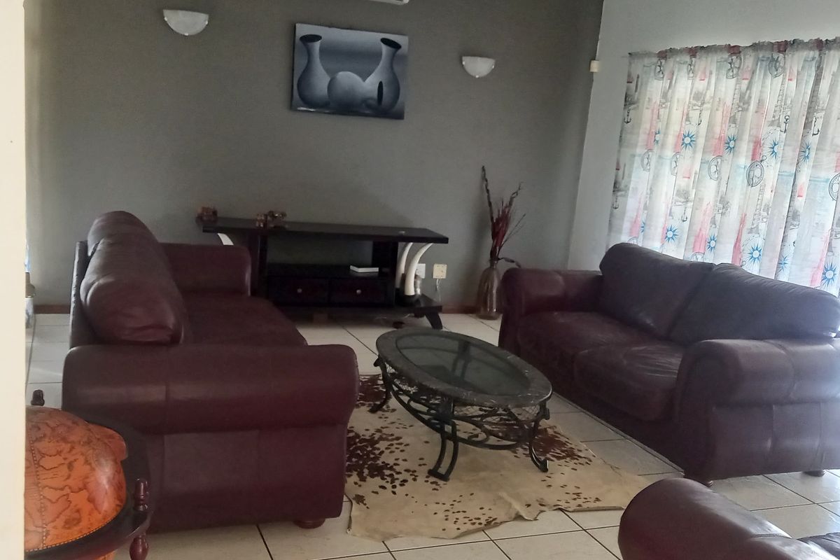 A living room featuring tiled flooring, a wall-mounted air conditioning unit, and ambient wall lighting.
