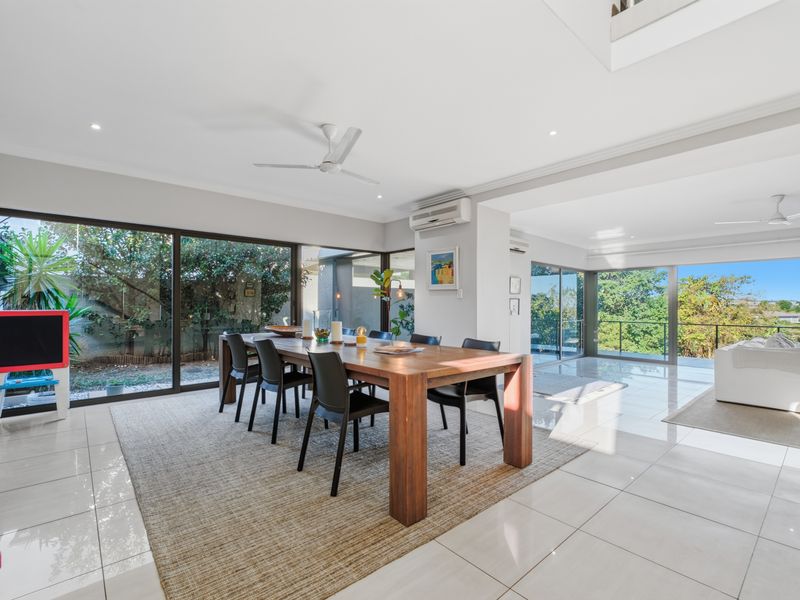 Spacious open-plan living and dining area featuring large sliding glass doors, tiled flooring, and modern ceiling fans with access to an outdoor balcony.