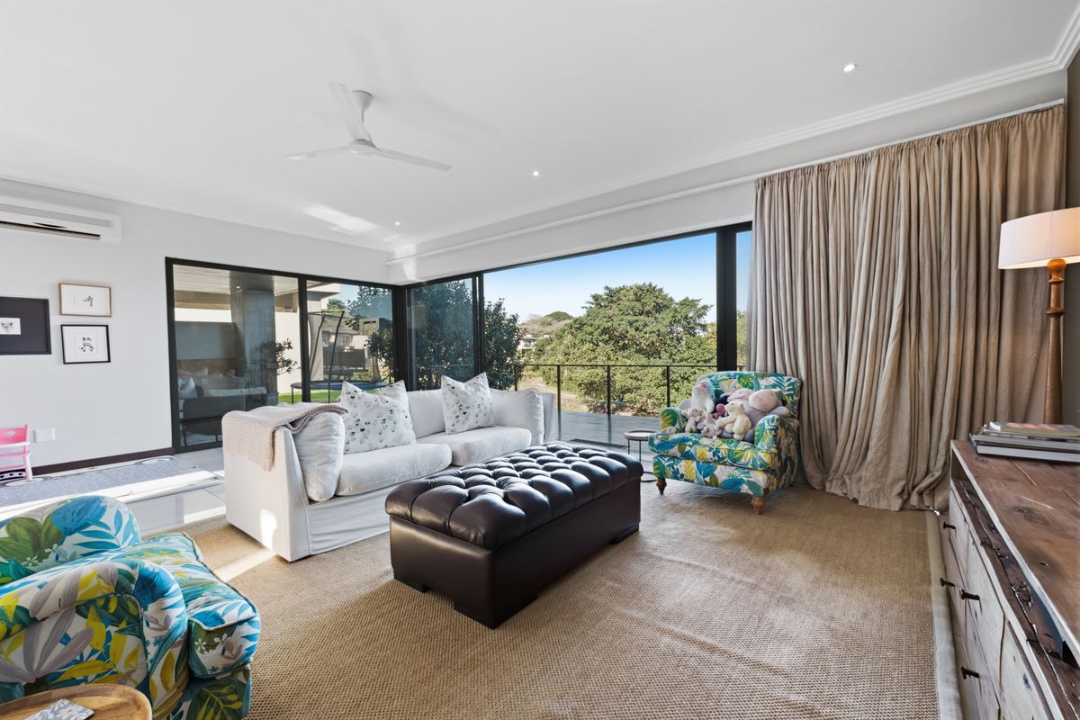 Bright living room featuring large sliding glass doors, recessed lighting, a ceiling fan, and split-system air conditioning, offering seamless access to the balcony.