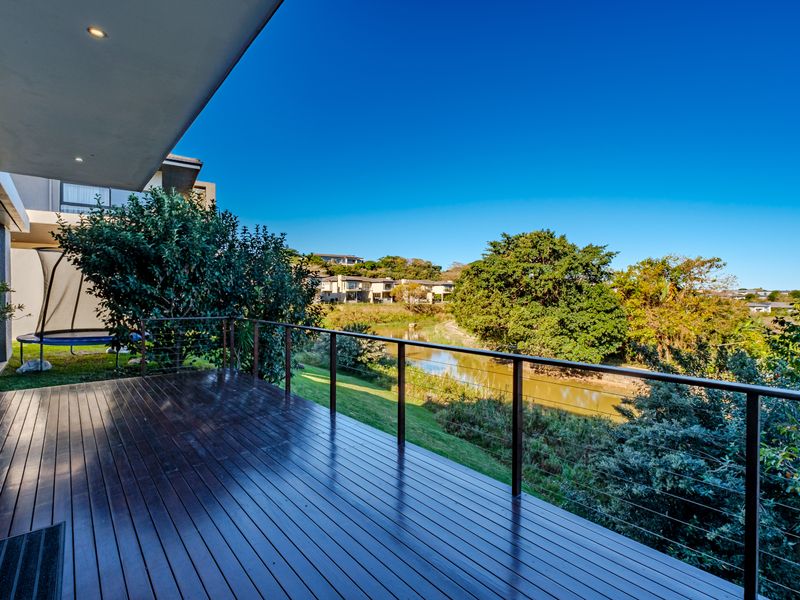 Spacious timber balcony featuring a modern metal balustrade and recessed lighting, offering scenic views over the river and surrounding landscape.