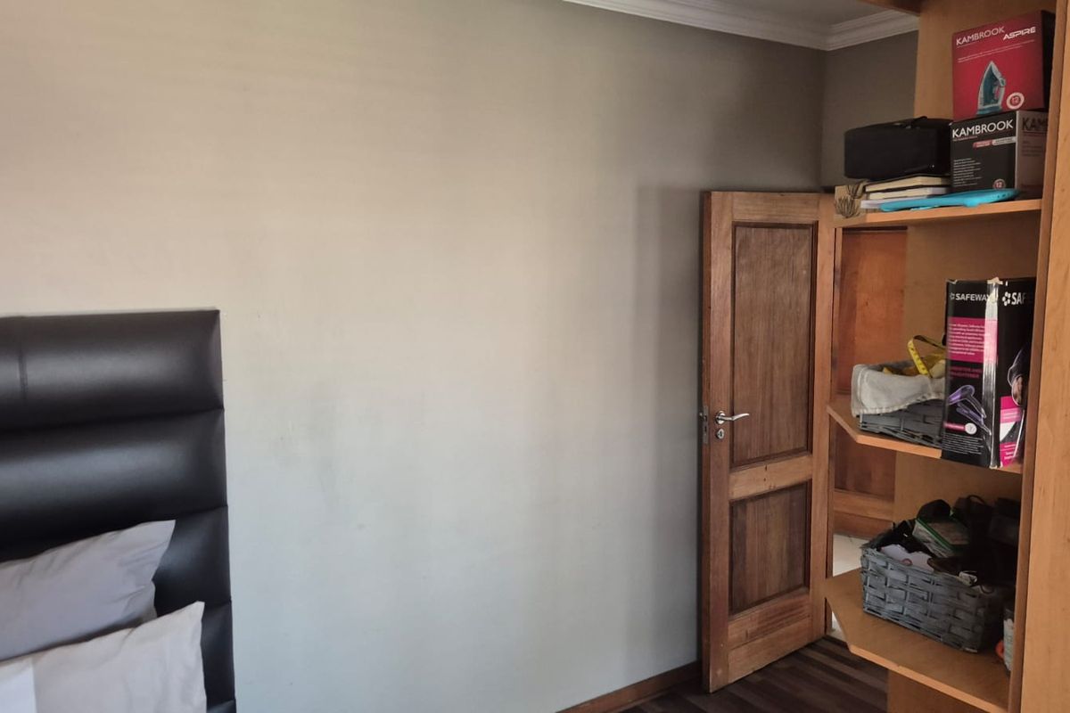 A bedroom featuring laminate flooring, a wooden door, and crown molding, providing a neutral base for interior design updates.