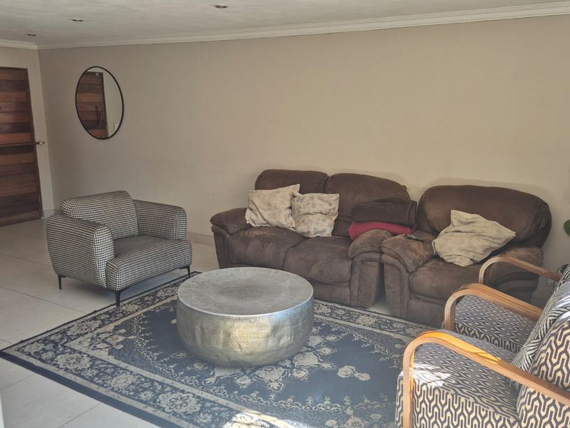 A spacious living room featuring neutral walls, tiled flooring, and recessed downlighting, providing a clean and functional base for interior design.