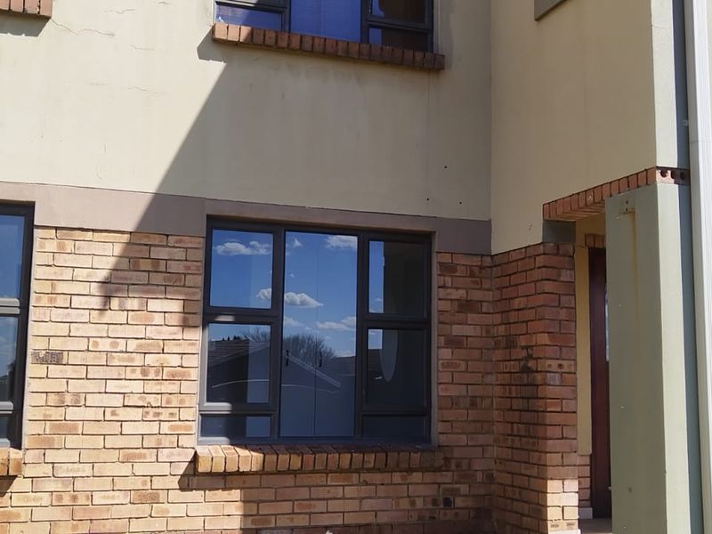 Front elevation of an apartment building featuring face brick accents, aluminium window frames, and a covered entrance area.