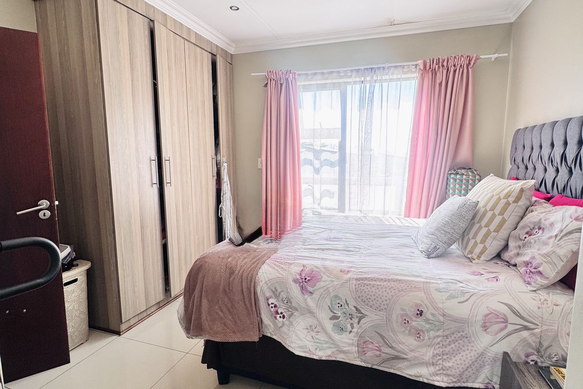 A well-maintained bedroom featuring built-in cupboards, large format floor tiles, and recessed downlighting, offering a clean and functional living space.