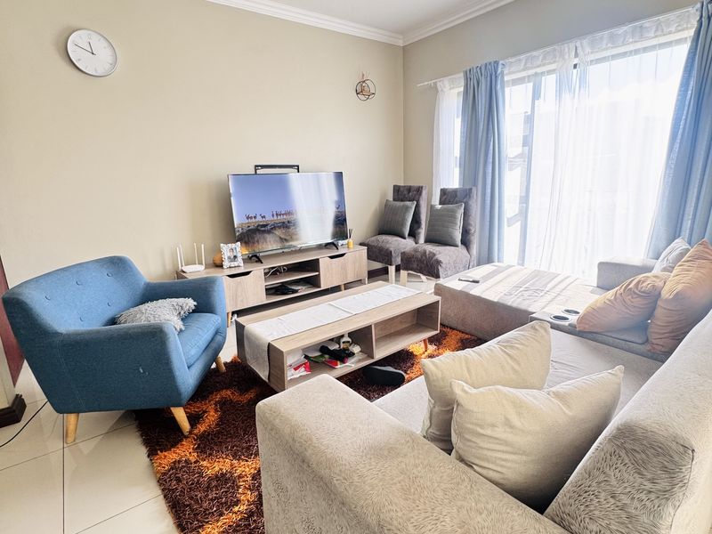 A bright and comfortable living room featuring large sliding glass doors that provide ample natural light and tiled flooring throughout.