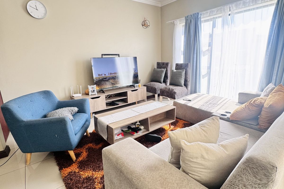 A bright and comfortable living room featuring large sliding glass doors that provide ample natural light and tiled flooring throughout.