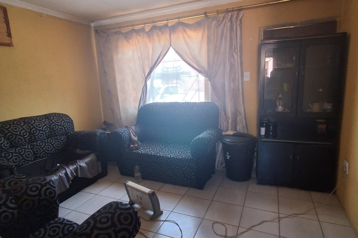 A living room featuring ceramic floor tiles and a built-in display cabinet, requiring cosmetic updates to improve the overall aesthetic.