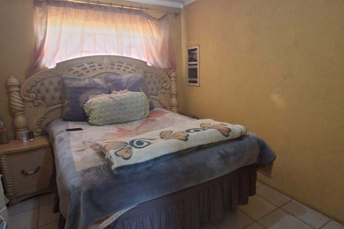 A bedroom featuring tiled flooring and standard wall finishes, requiring cosmetic updates to improve the overall aesthetic and condition.