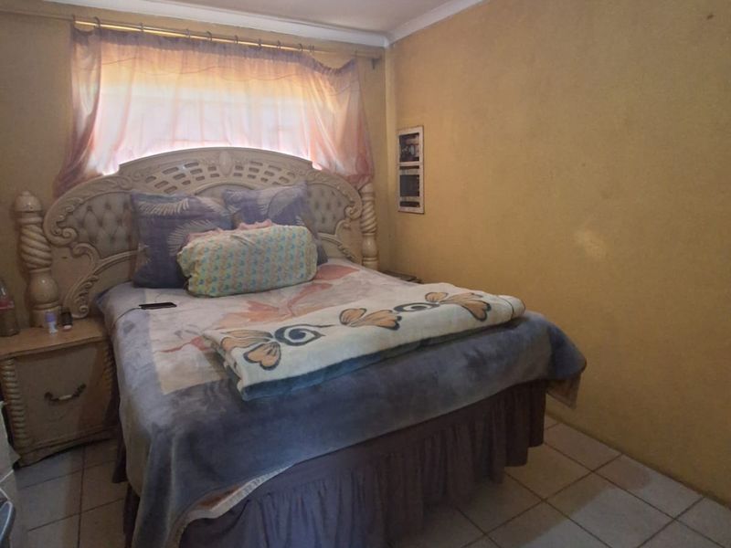 A bedroom featuring tiled flooring and standard wall finishes, requiring cosmetic updates to improve the overall aesthetic and condition.