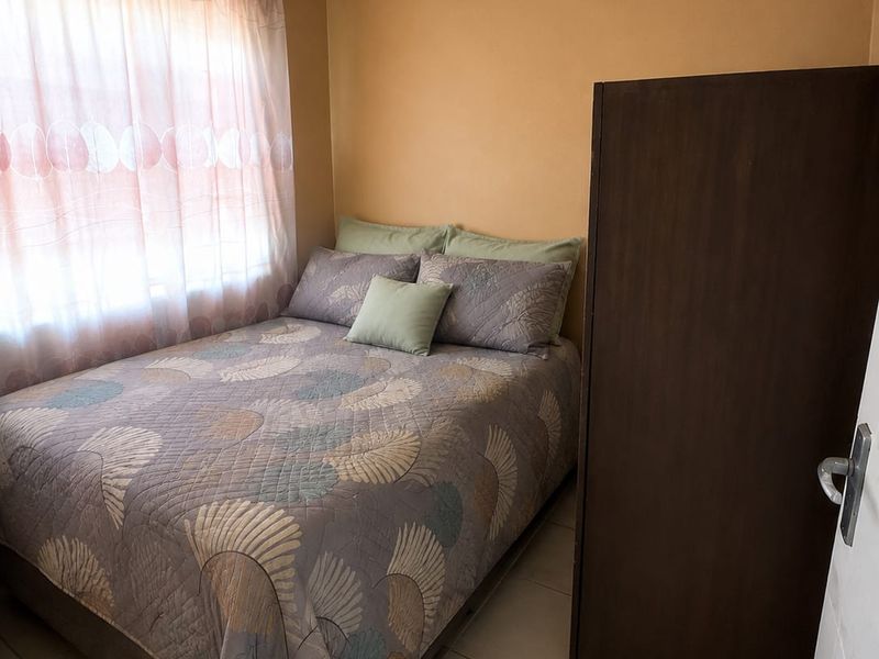 A compact bedroom featuring tiled flooring and neutral wall finishes, providing a functional space with natural light from the window.