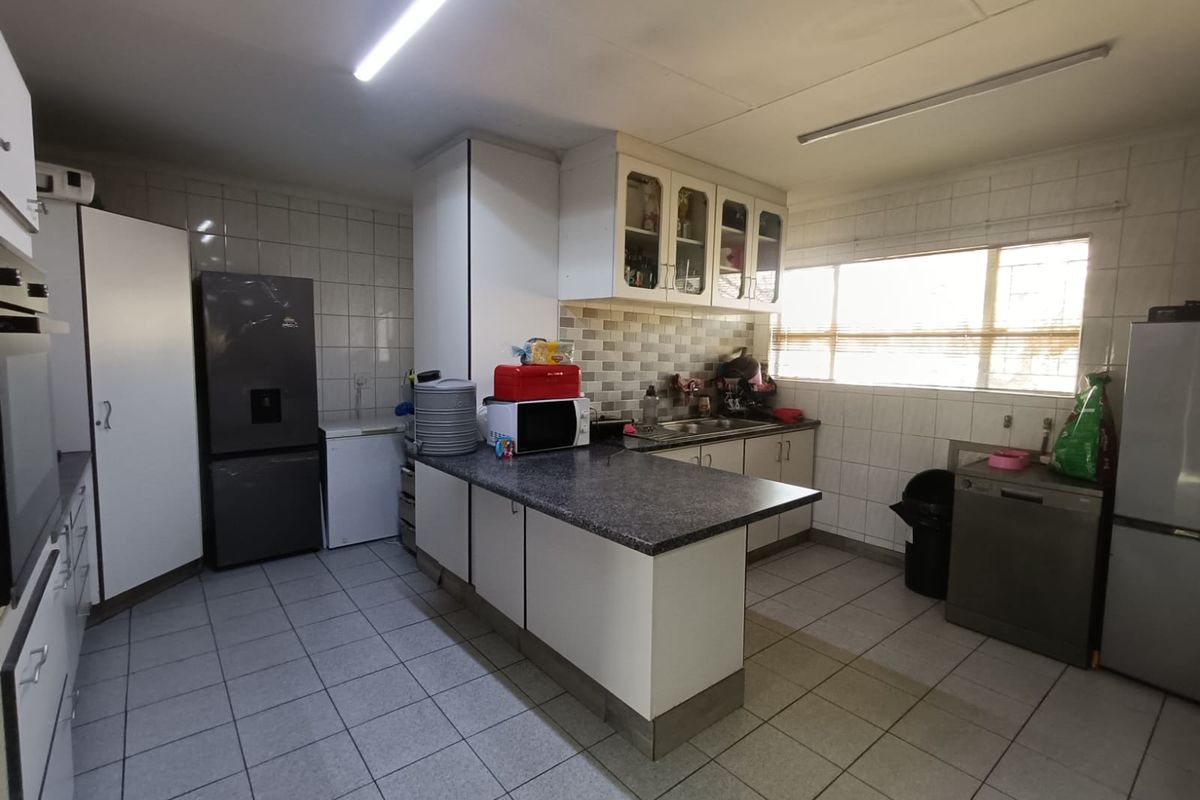 Functional kitchen featuring ample built-in cabinetry, laminate countertops, double sink, and tiled finishes throughout.