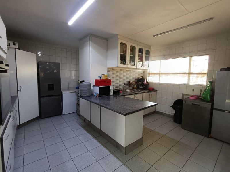 Functional kitchen featuring ample built-in cabinetry, laminate countertops, double sink, and tiled finishes throughout.
