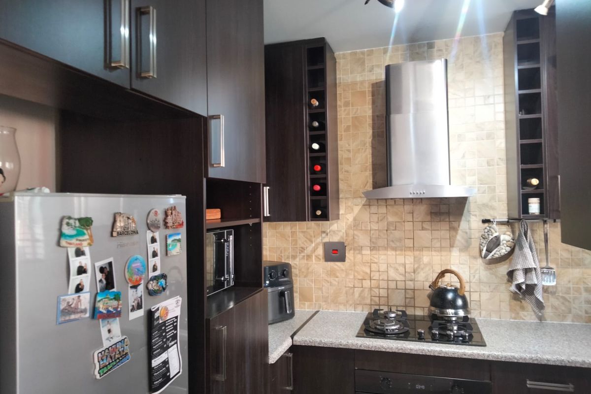 A functional kitchen featuring dark wood cabinetry, mosaic tile backsplash, stainless steel extractor fan, built-in oven, and a gas hob.