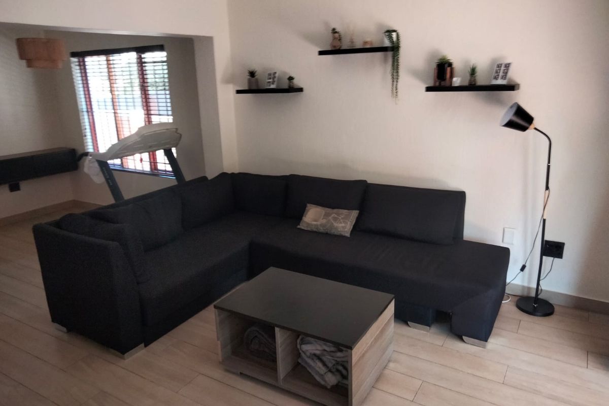A well-maintained living room featuring modern tiled flooring, neutral wall finishes, and natural light through window blinds.