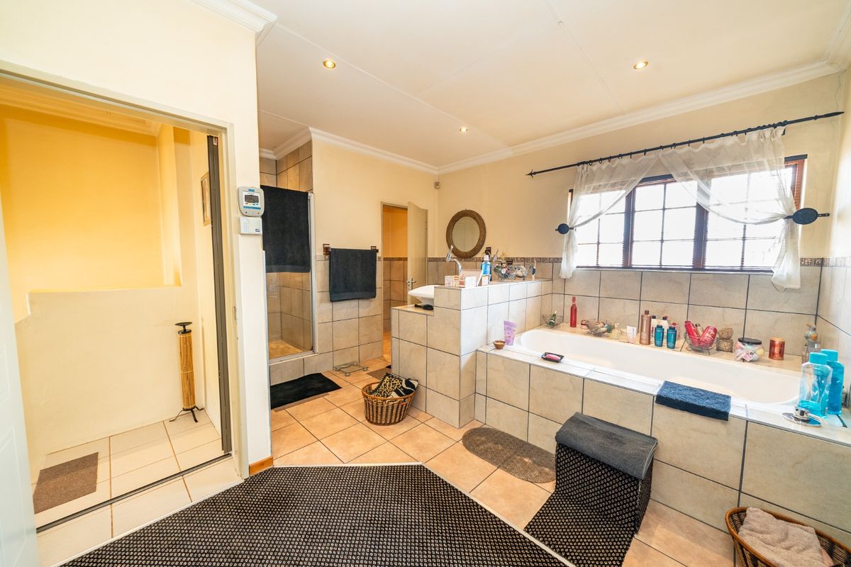 Spacious bathroom featuring a built-in bathtub, separate shower enclosure, and neutral tiled finishes throughout.