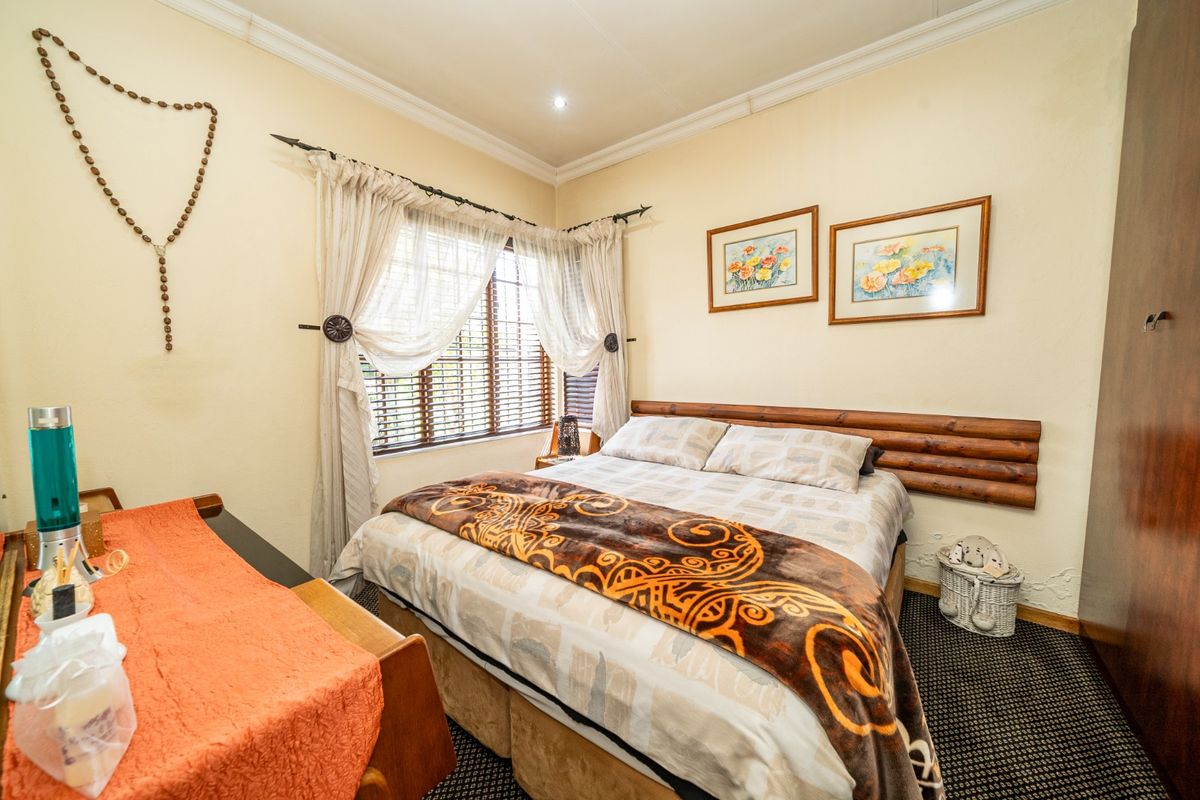 A cozy bedroom featuring a built-in wardrobe, wooden headboard, and venetian blinds, offering a functional space with classic finishes.