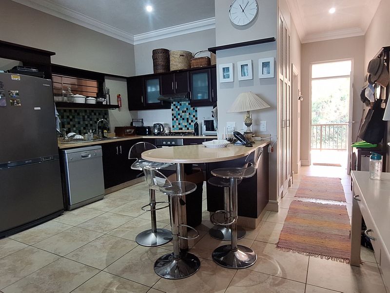 A functional kitchen featuring dark cabinetry, a tiled backsplash, and a built-in breakfast bar, with direct access to an outdoor balcony area.