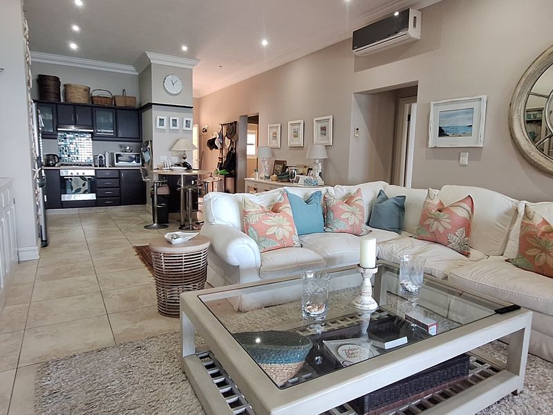 Spacious open-plan living area featuring tiled floors, recessed lighting, a split-system air conditioner, and a well-appointed kitchen with built-in cabinetry and appliances.