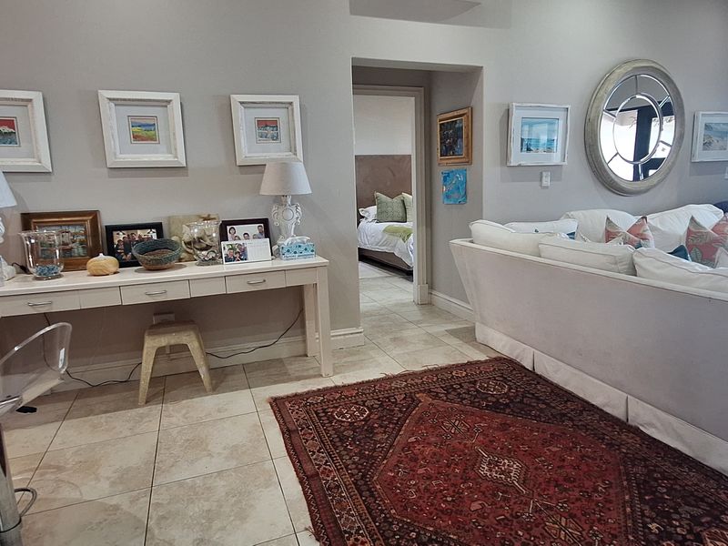 A spacious living area featuring neutral wall tones, tiled flooring, and direct access to adjacent rooms and an outdoor balcony.